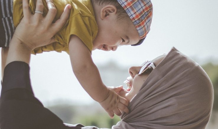 woman holding boy during daytime