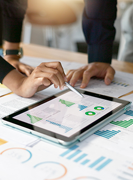 Two people review financial charts on a tablet, with one person using a stylus to point at the screen.