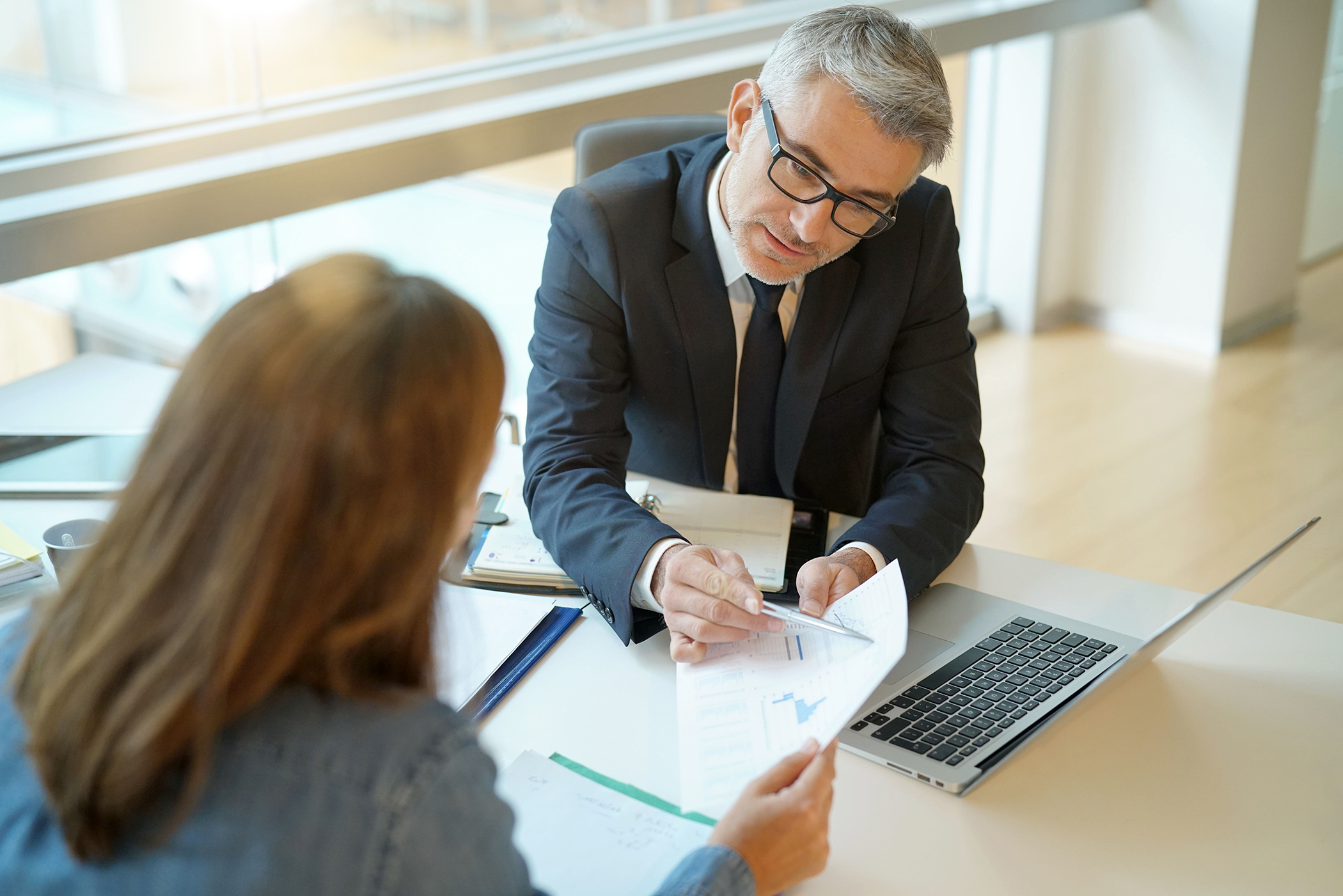 Commercial banker reviewing financial information with a business client during a strategic lending consultation.